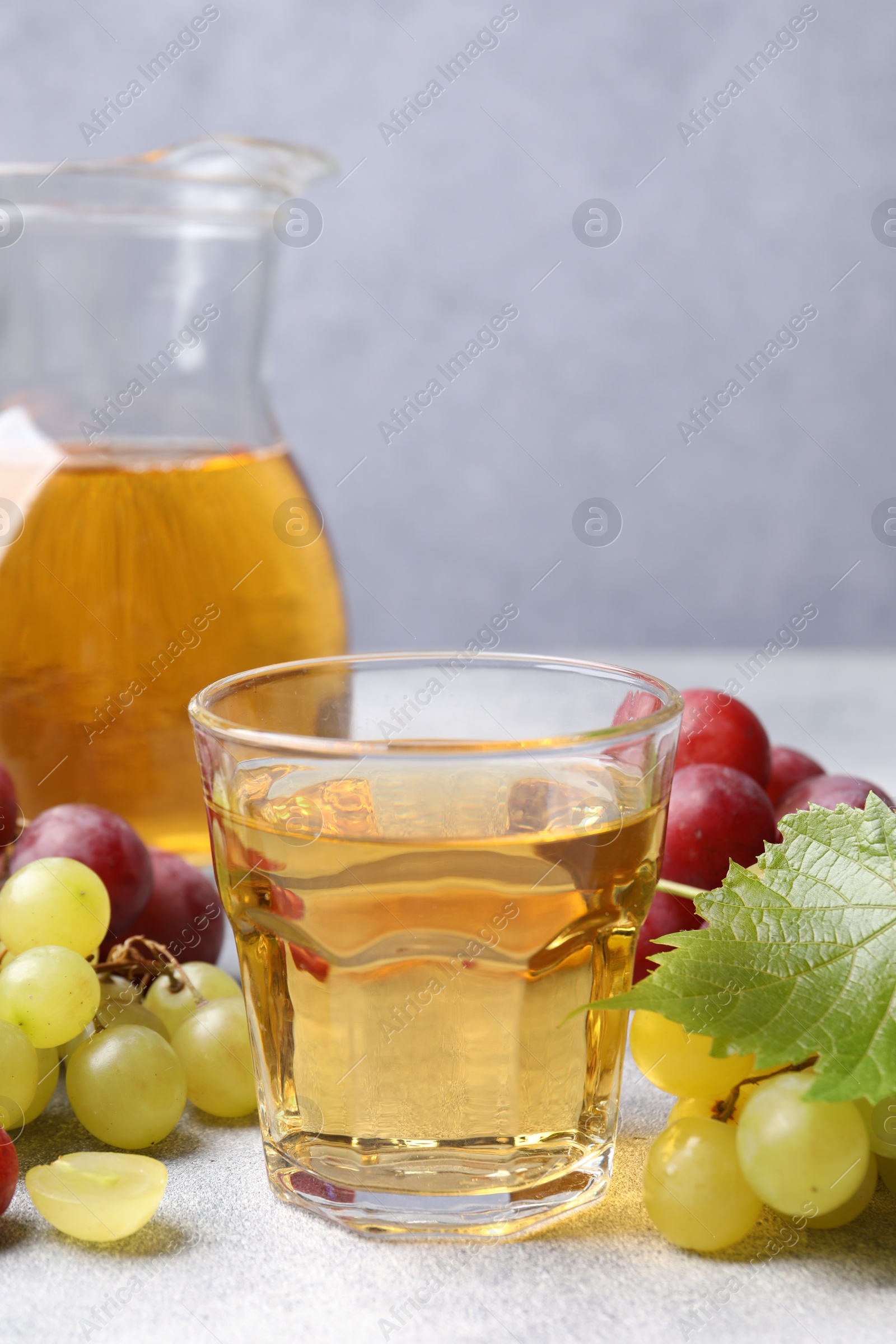 Photo of Ripe grapes and tasty juice on grey table