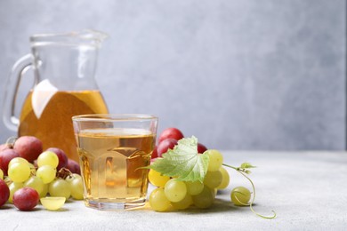 Ripe grapes and tasty juice on grey table. Space for text