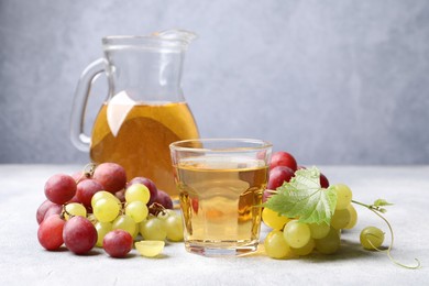 Photo of Ripe grapes and tasty juice on grey table