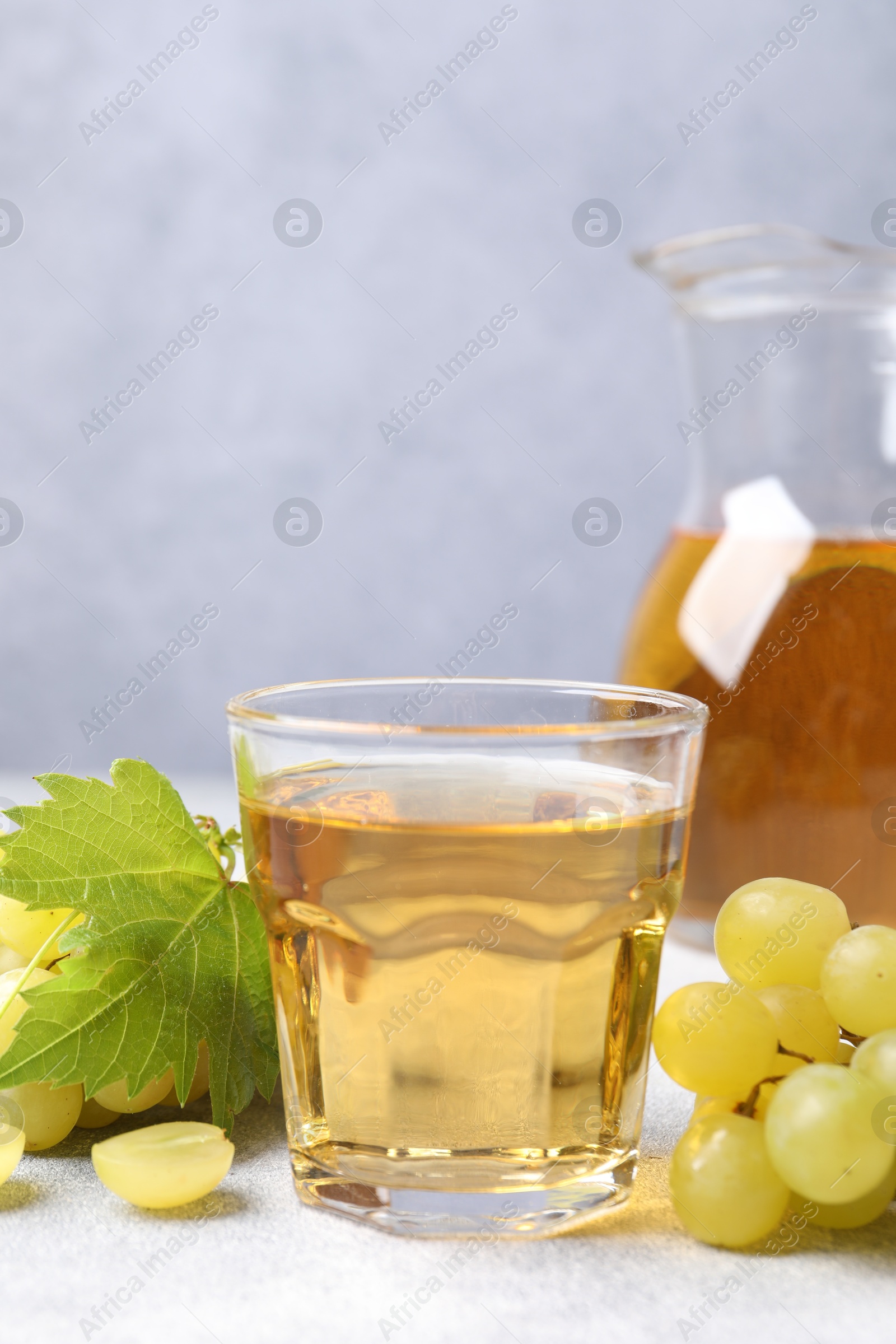 Photo of Ripe grapes and tasty juice on grey table