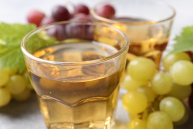 Photo of Ripe grapes and of tasty juice on grey table, closeup