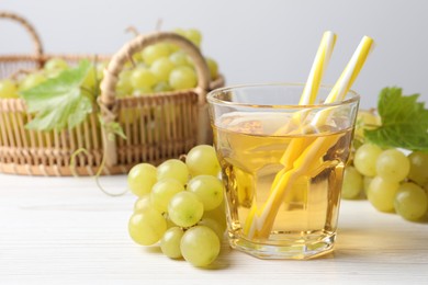 Photo of Ripe grapes and glass of tasty juice on white wooden table