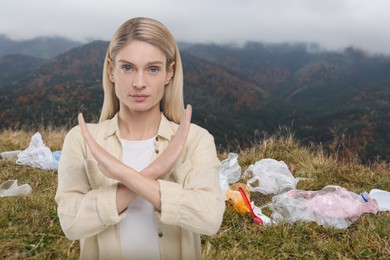 Image of Environmental pollution. Woman showing stop gesture among garbage on mountain hill
