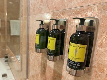 Photo of Berlin, Germany - July 2, 2024: Bottles with body care products on tiled wall in Regent Berlin Hotel bathroom