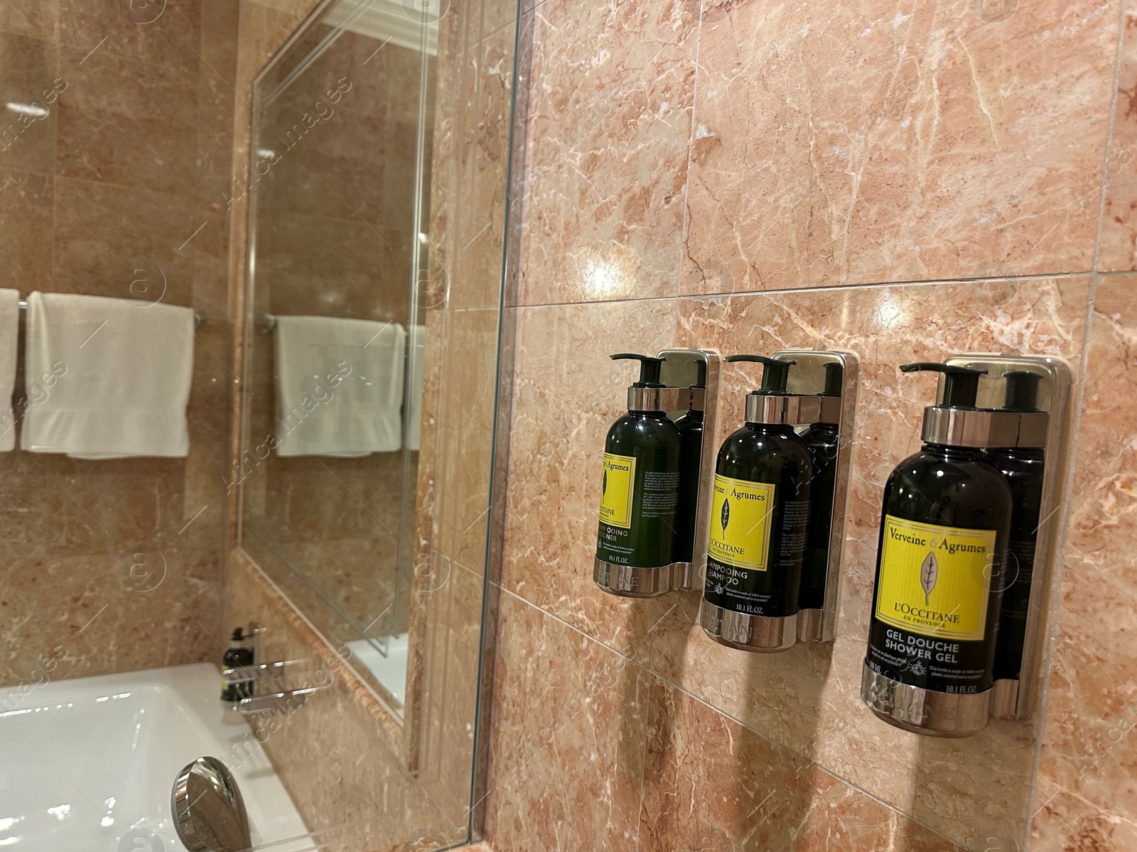 Photo of Berlin, Germany - July 2, 2024: Bottles with body care products on tiled wall in Regent Berlin Hotel bathroom