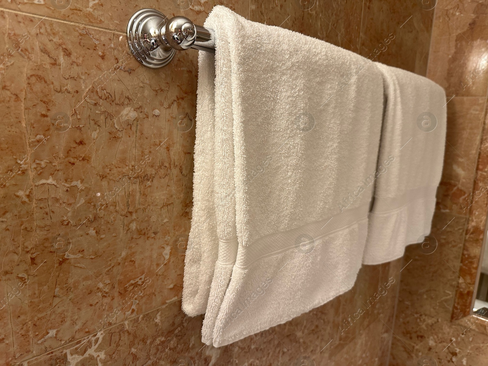 Photo of Soft terry towels hanging on tiled wall in hotel bathroom