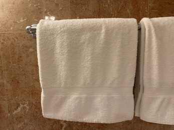 Photo of Soft terry towels hanging on tiled wall in hotel bathroom