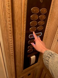 Woman pressing elevator button in luxury hotel, closeup