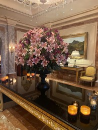 Luxury hotel interior. Beautiful bouquet on mirrored table and stylish chandelier in lobby