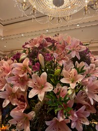 Photo of Luxury hotel interior. Beautiful bouquet of pink lilies and stylish chandelier in lobby