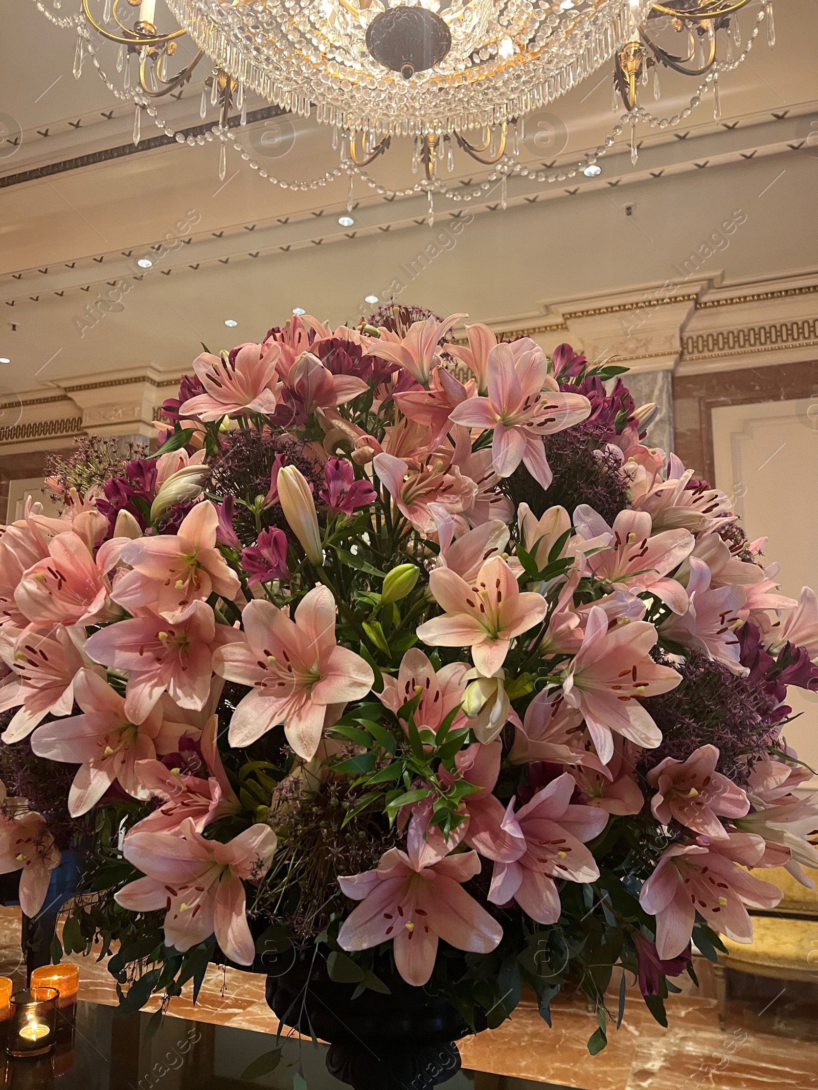 Photo of Luxury hotel interior. Beautiful bouquet of pink lilies and stylish chandelier in lobby