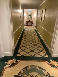 Photo of Luxury hotel interior. Empty long corridor with carpet and pictures