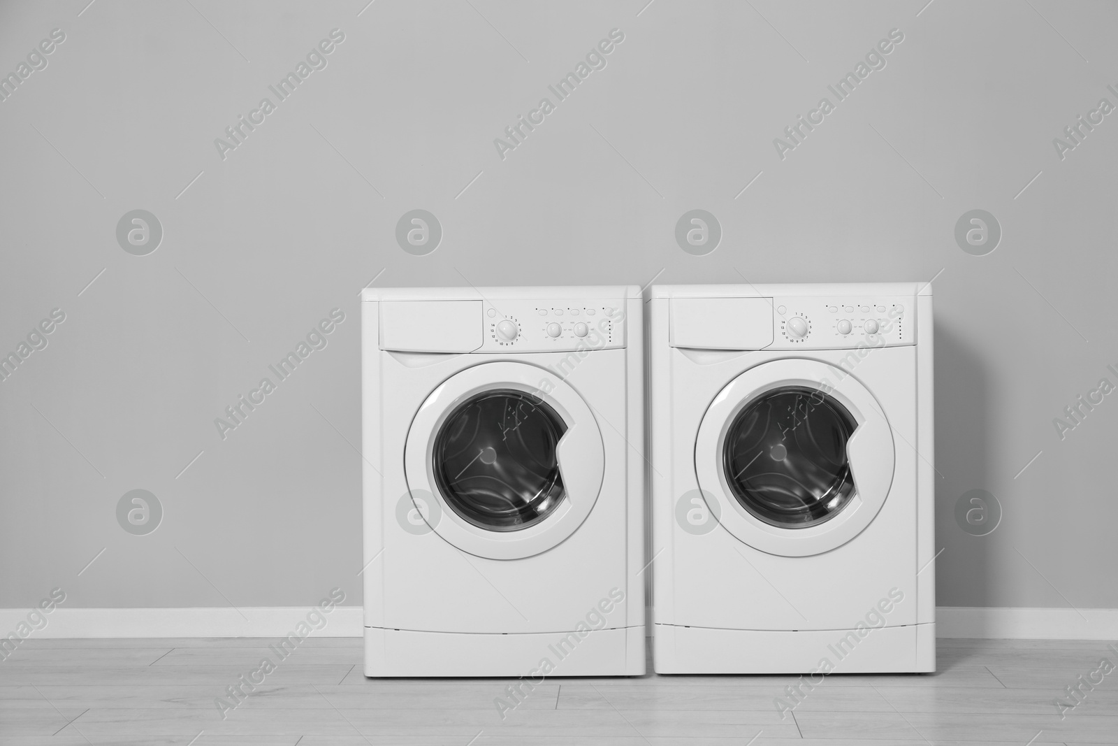 Image of Two washing machines near grey wall in laundry room