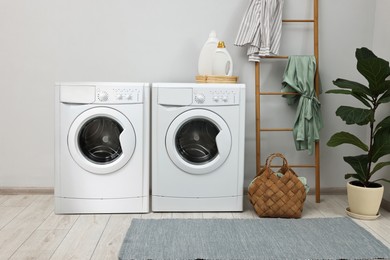 Two washing machines near light grey wall in laundry room