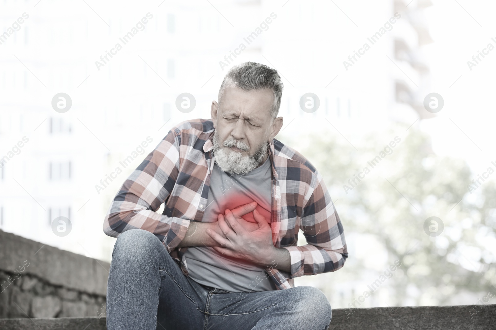 Image of Heart attack. Mature man suffering from pain in chest outdoors