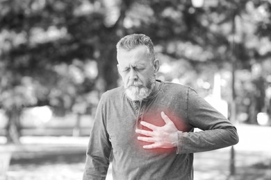 Image of Heart attack. Mature man suffering from pain in chest outdoors