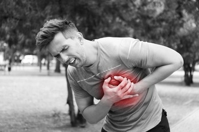 Image of Heart attack. Man writhing in pain and pressing hands to chest outdoors