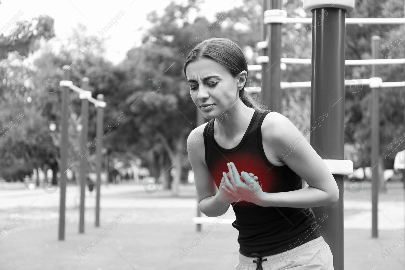 Image of Heart attack. Woman suffering from pain and pressing hands to chest at outdoor gym