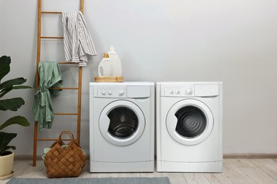 Two washing machines near light grey wall in laundry room