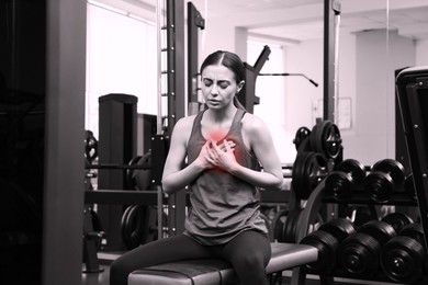 Image of Heart attack. Young woman suffering from pain and pressing hands to chest at gym