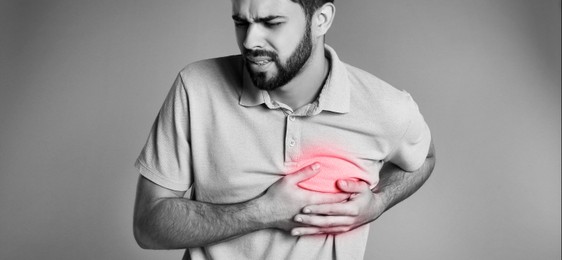 Image of Heart attack. Young man suffering from pain and pressing hands to chest on grey background. Banner design