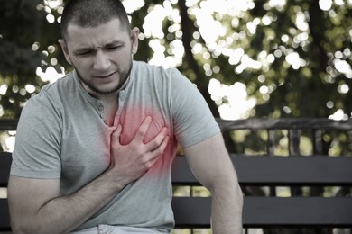 Image of Heart attack. Young man suffering from pain and pressing hand to chest outdoors