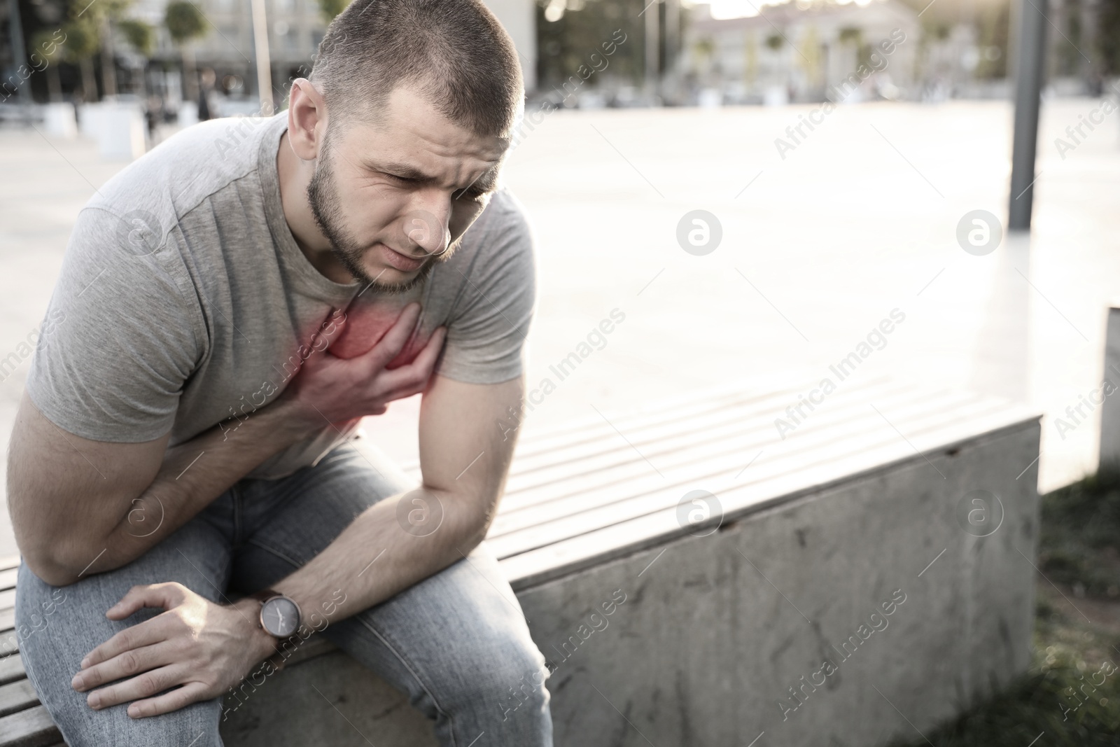 Image of Heart attack. Young man suffering from pain in chest outdoors