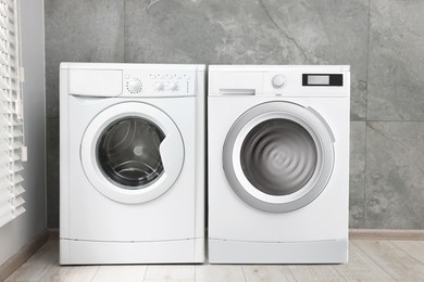 Image of Two washing machines near tiled wall in laundry room