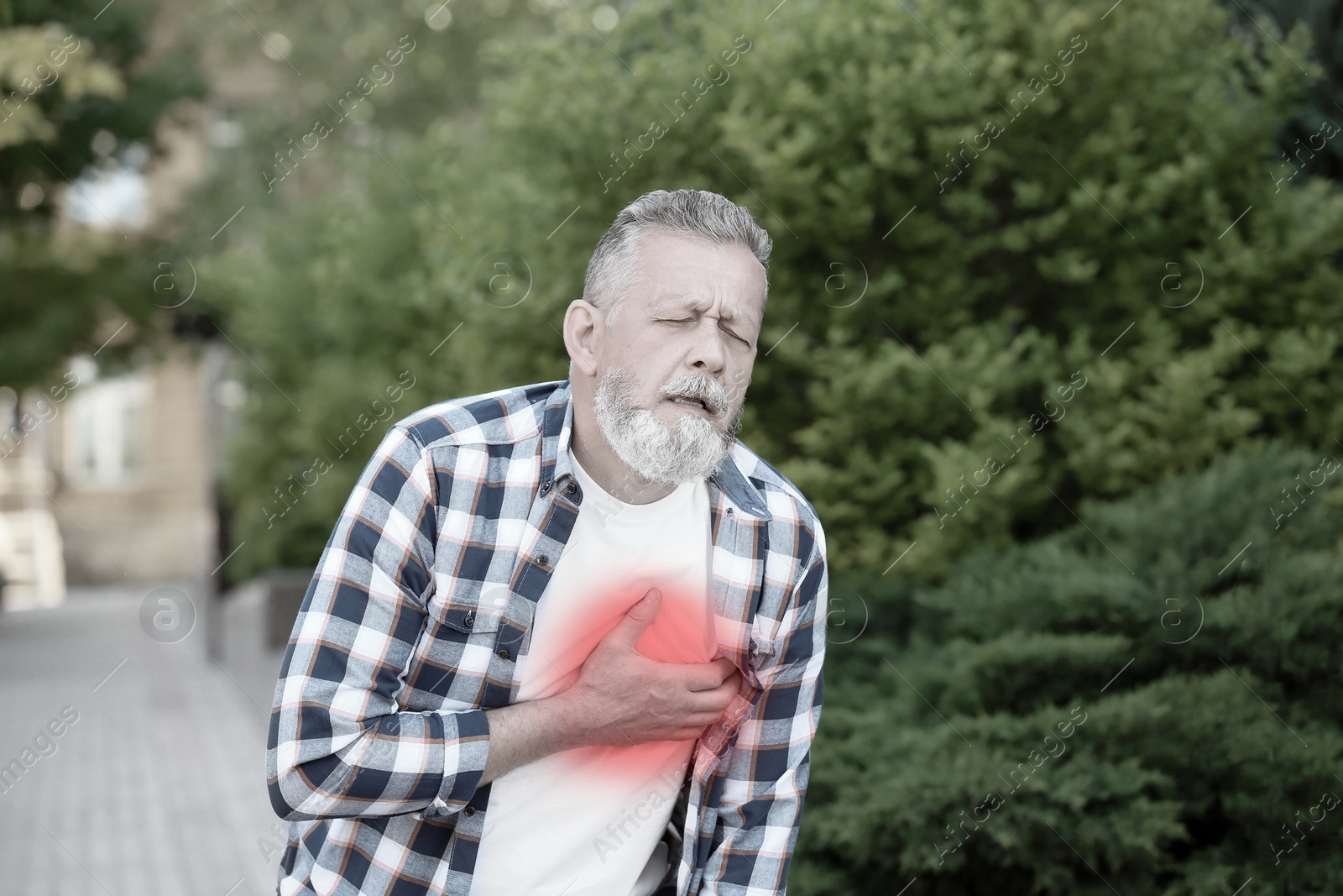 Image of Heart attack. Mature man suffering from pain in chest outdoors