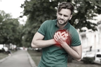 Image of Heart attack. Man suffering from pain and pressing hands to chest outdoors