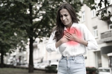 Image of Heart attack. Woman suffering from pain and pressing hands to chest outdoors