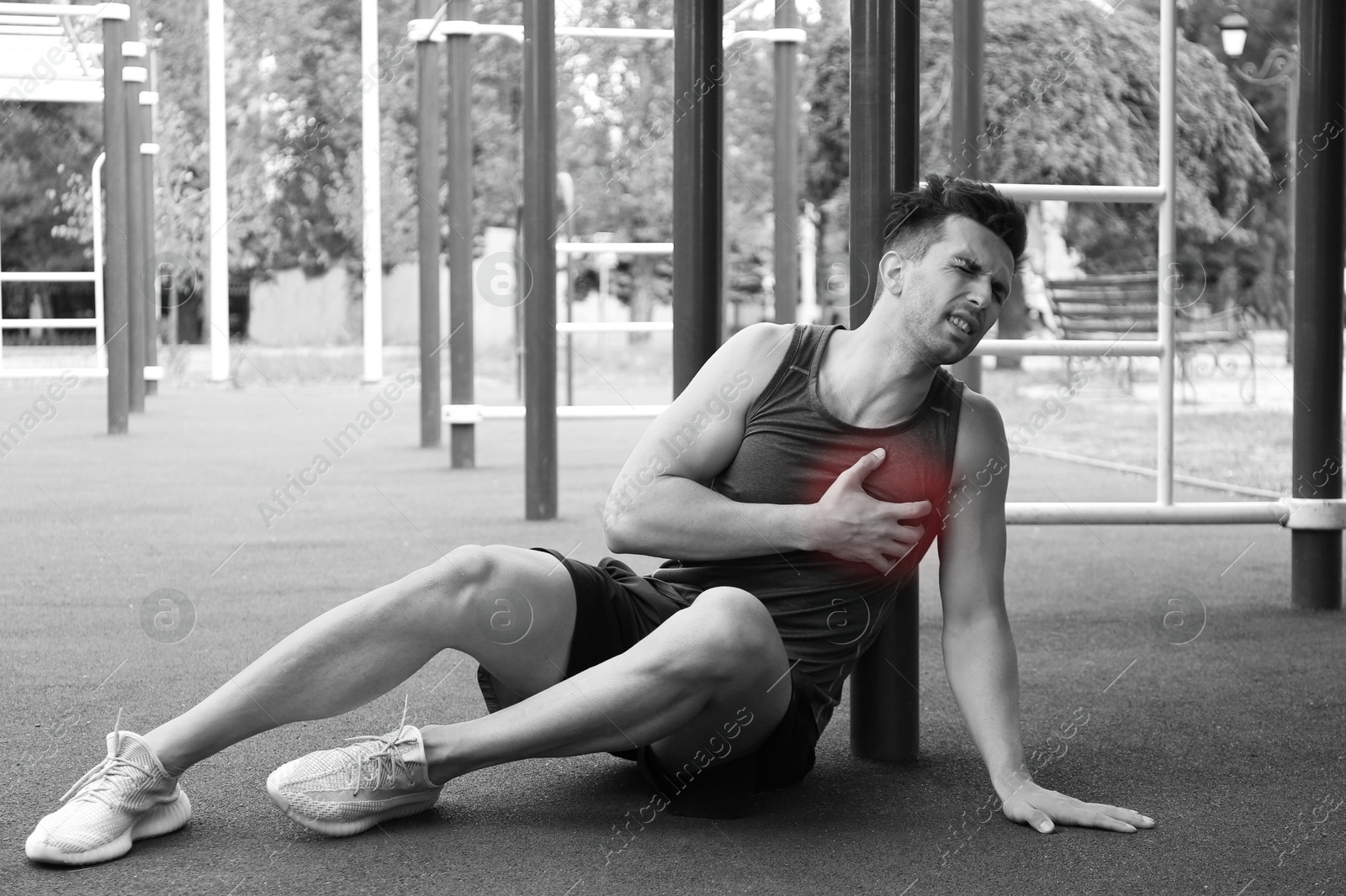 Image of Heart attack. Man writhing in pain and pressing hand to chest at outdoor gym