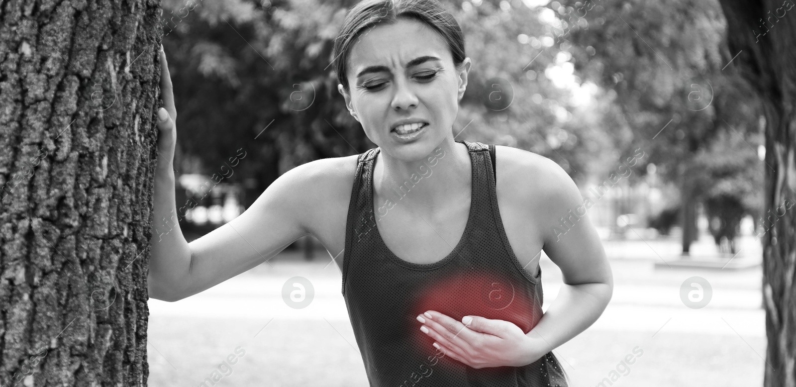 Image of Heart attack. Young woman suffering from pain in chest and leaning on tree outdoors. Banner design