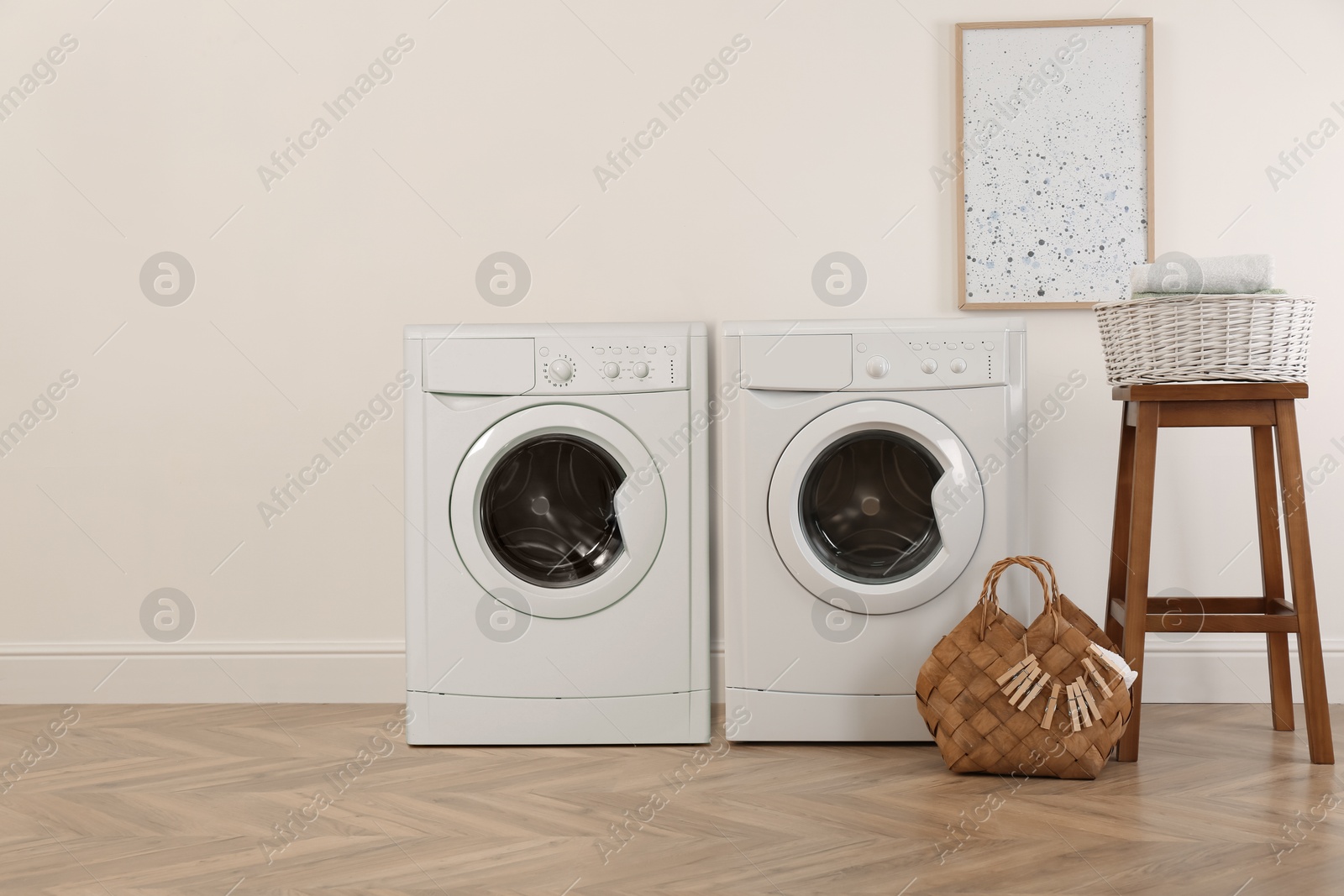 Image of Two washing machines near beige wall in laundry room