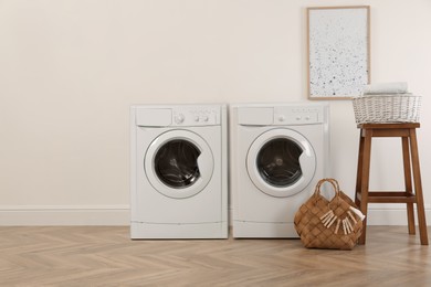 Image of Two washing machines near beige wall in laundry room