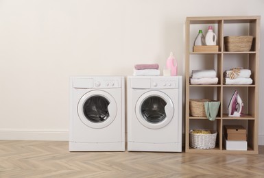 Image of Two washing machines near beige wall in laundry room