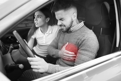 Image of Heart attack. Man suffering from pain in chest while driving, his worried girlfriend trying to stop car