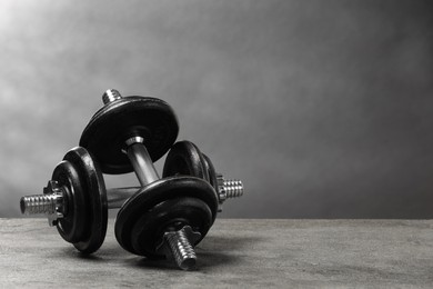 Photo of Two barbells on grey textured table. Space for text