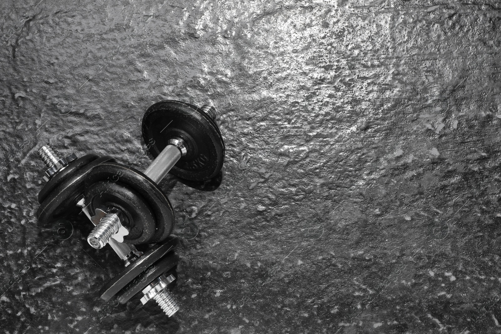 Photo of Barbells on dark textured floor, top view. Space for text