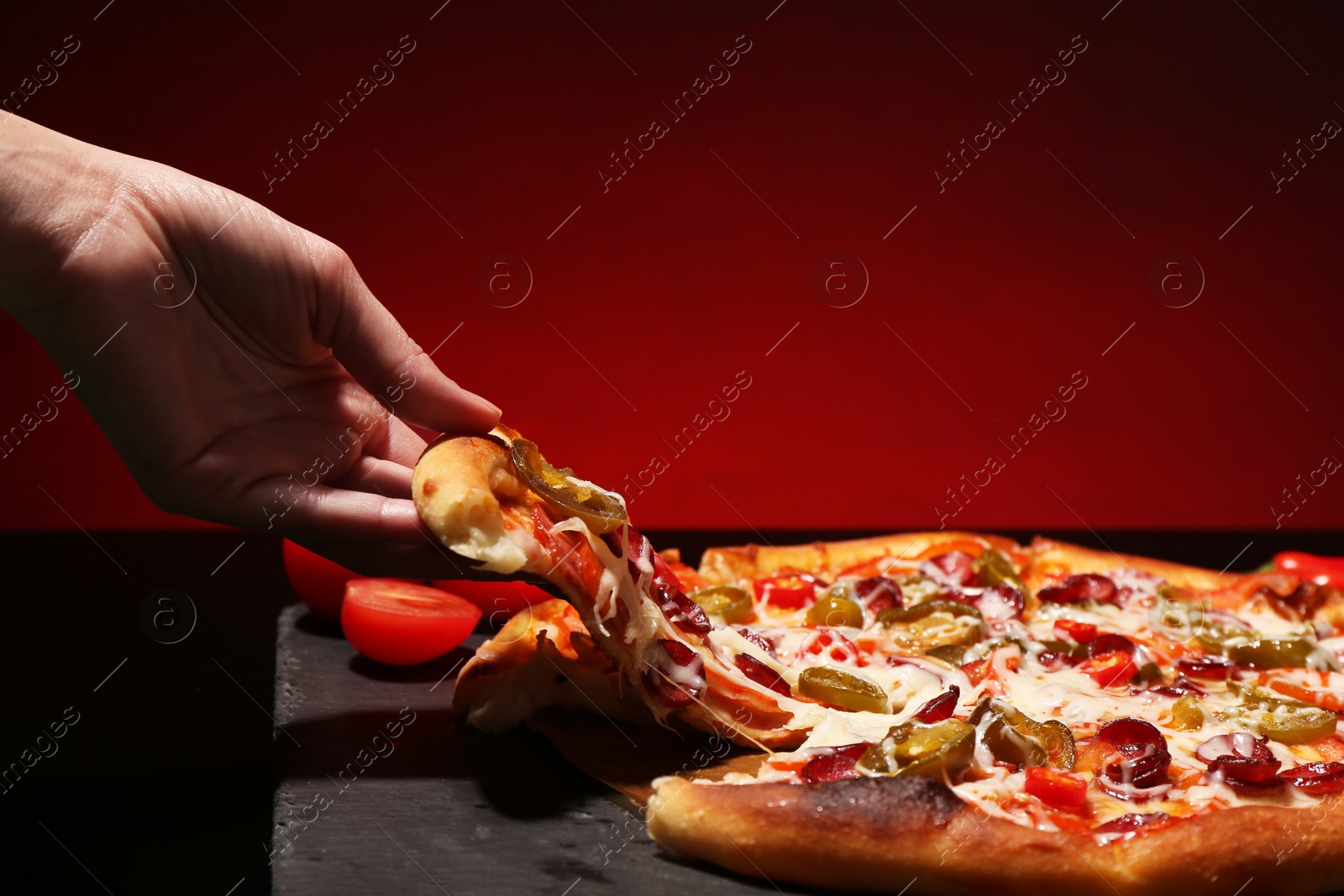 Photo of Woman taking piece of delicious pizza Diablo on red background, closeup. Space for text