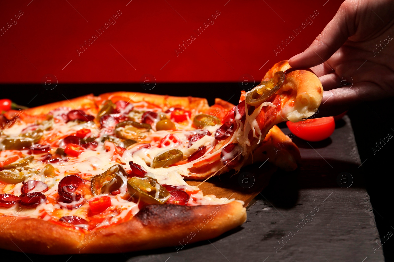 Photo of Woman taking piece of delicious pizza Diablo on red background, closeup