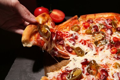 Photo of Woman taking piece of delicious pizza Diablo on black background, closeup