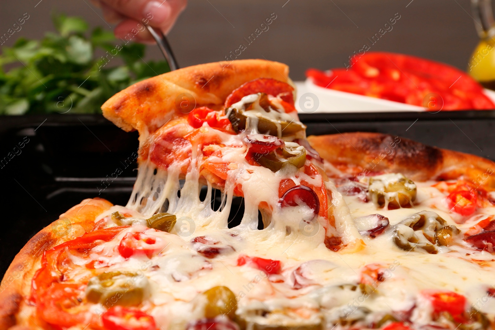 Photo of Woman taking piece of delicious pizza Diablo from baking tray, closeup