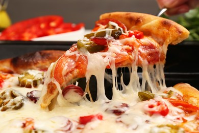 Photo of Woman taking piece of delicious pizza Diablo from baking tray, closeup