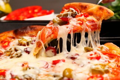 Taking piece of delicious pizza Diablo from baking tray, closeup