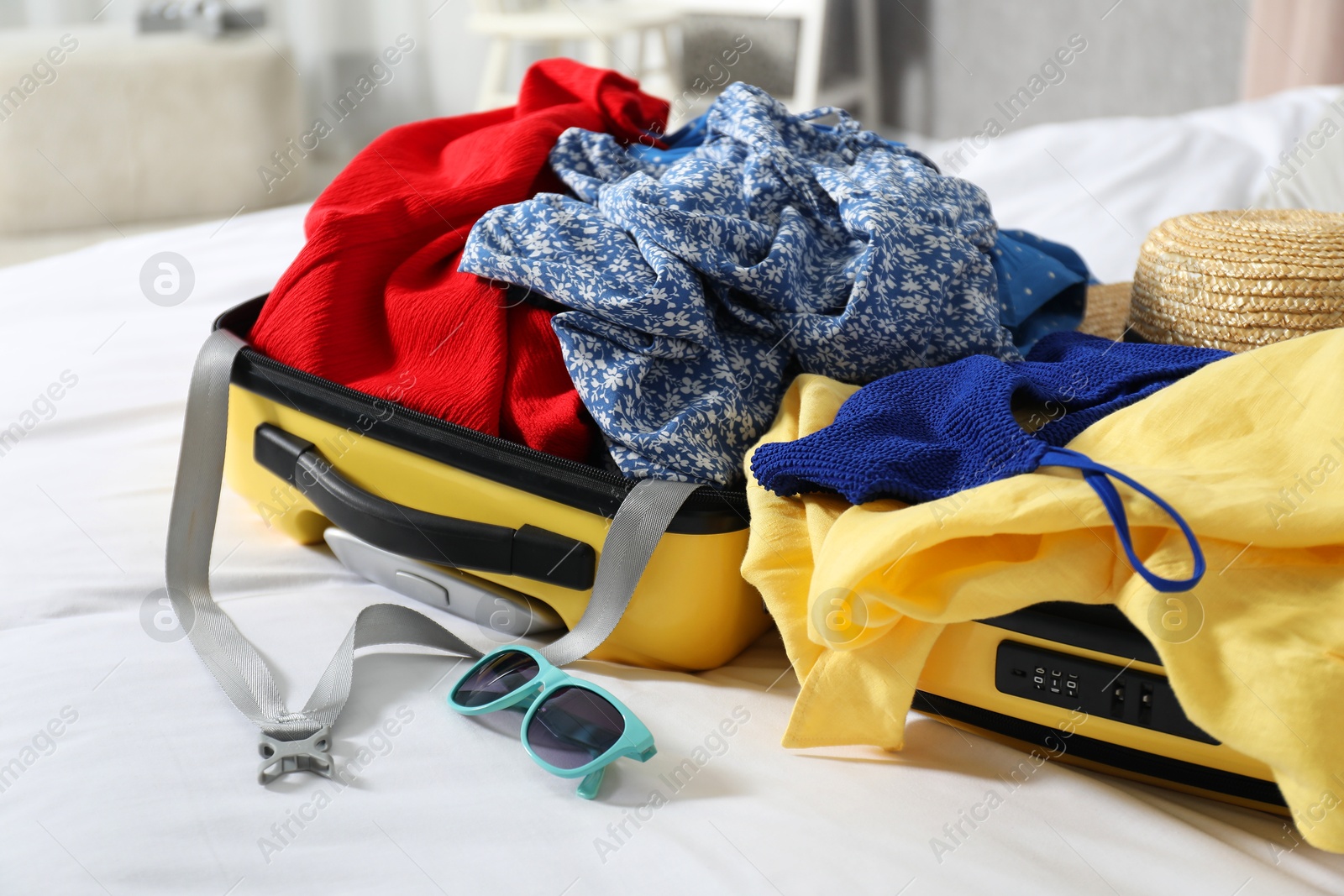 Photo of Open suitcase with traveler's belongings on bed, closeup