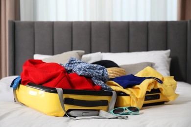 Photo of Open suitcase with traveler's belongings on bed