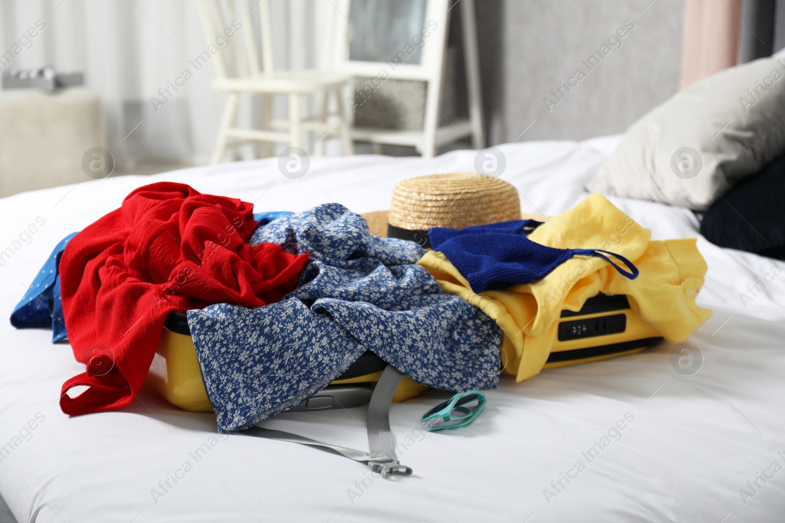 Photo of Open suitcase with traveler's belongings on bed