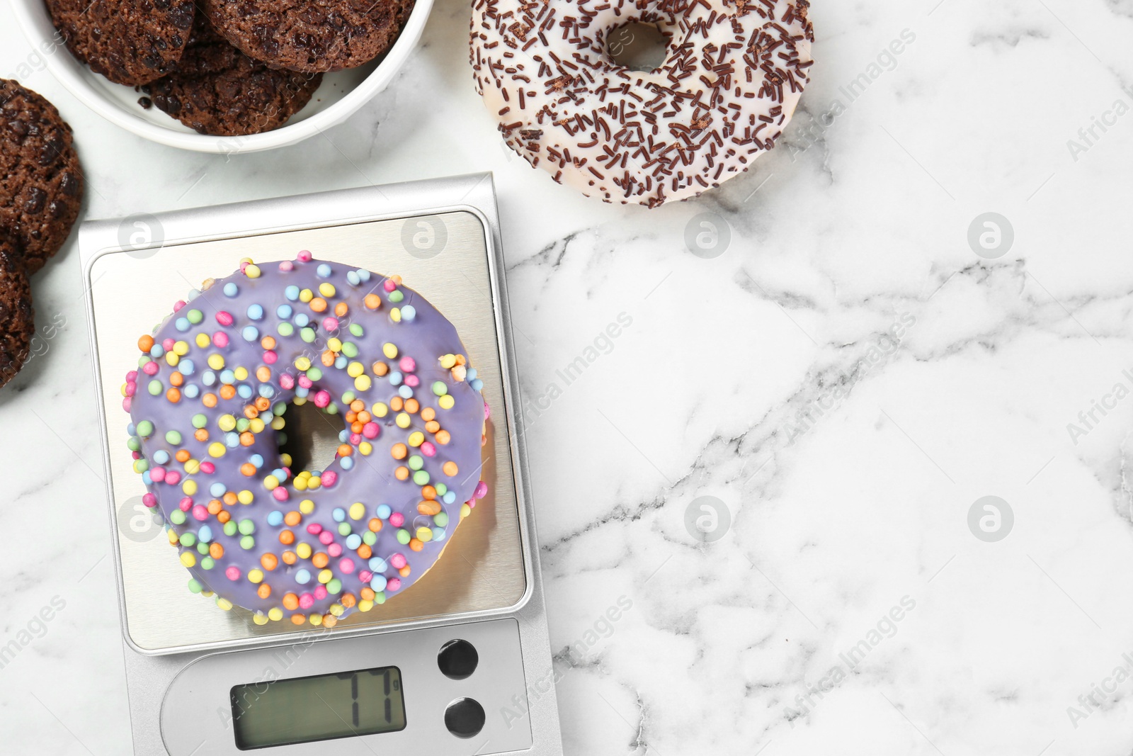 Photo of Flat lay composition of kitchen scale with donut on white marble table. Space for text