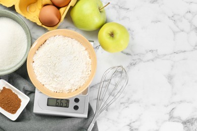 Photo of Flat lay composition of kitchen scale with bowl of flour and products on white marble table. Space for text